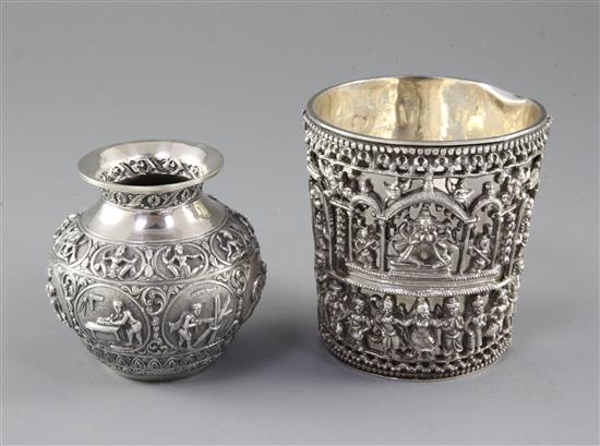 An Indian white metal beaker, with cast cased mount depicting Lord Shiva within a shrine and bands of figures and a small vase